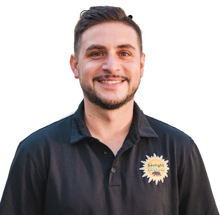 A man with a friendly smile is wearing a black polo shirt embroidered with a logo featuring a stylized sun. He has short, neatly styled dark hair and a trimmed beard. The background is removed, highlighting only his upper body in the image.